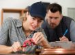 gas fitting male teacher watching female student pipe fitting