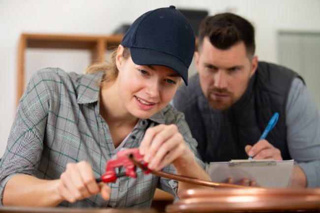 gas fitting male teacher watching female student pipe fitting