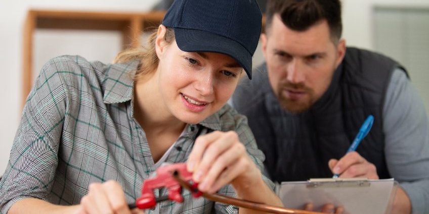 gas fitting male teacher watching female student pipe fitting