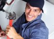 Handsome plumber fixing a sink in a kitchen sink