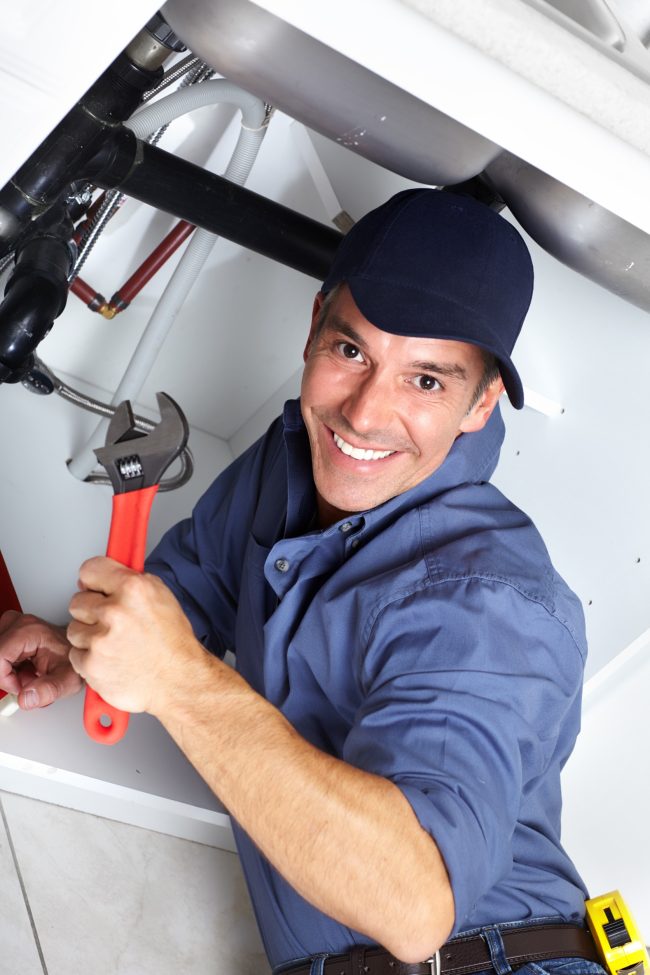 Handsome plumber fixing a sink in a kitchen sink