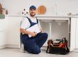Male plumber with clipboard near sink in kitchen