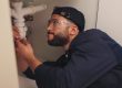 Plumber working on filter system improvement for small business in house