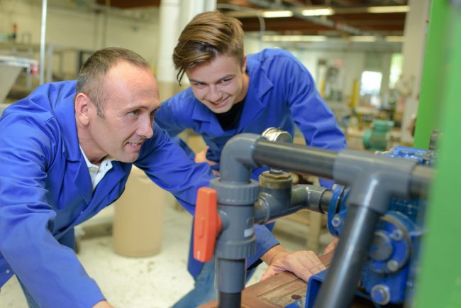 Man and apprentice looking at machinery